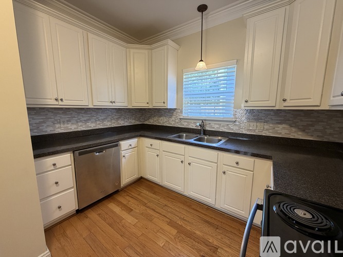 A kitchen with white cabinets and a black countertop.