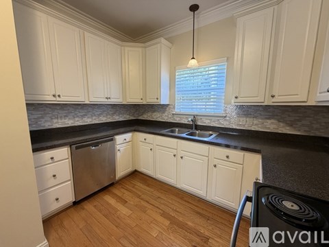 A kitchen with white cabinets and a black countertop.