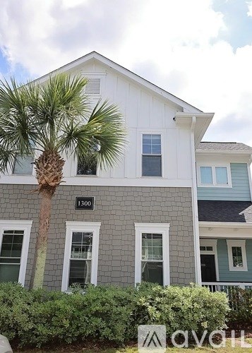 A white house with a palm tree in front.
