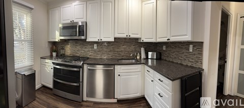 A kitchen with white cabinets and a black countertop.