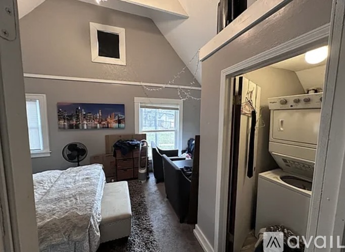 A bedroom with a bed, a fan, and a window with a cityscape view.