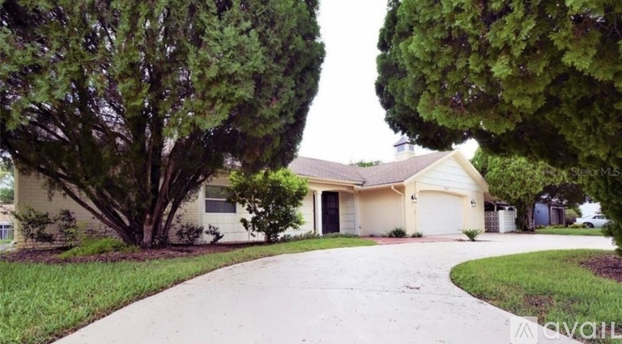A house with a driveway and trees in front of it.