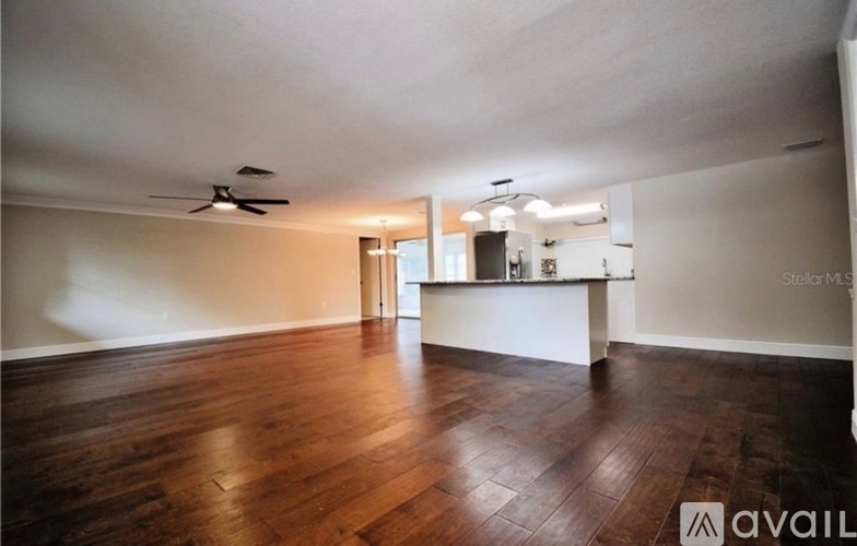 A spacious room with wooden floors and a ceiling fan.