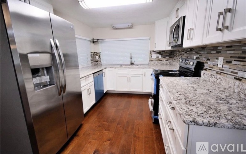 A kitchen with a stainless steel refrigerator and a granite countertop.