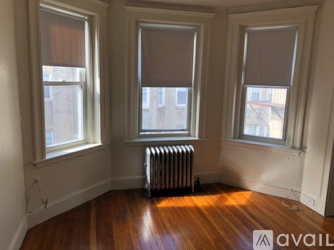 A room with wooden floors and three windows.