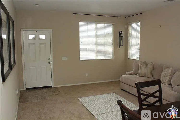 A living room with a couch, chair, and window with blinds.