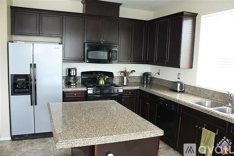 A kitchen with brown cabinets and a granite counter.