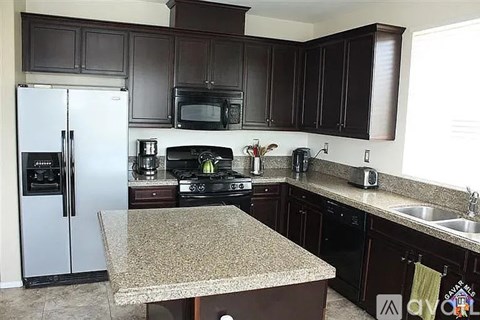 A kitchen with brown cabinets and a granite counter.