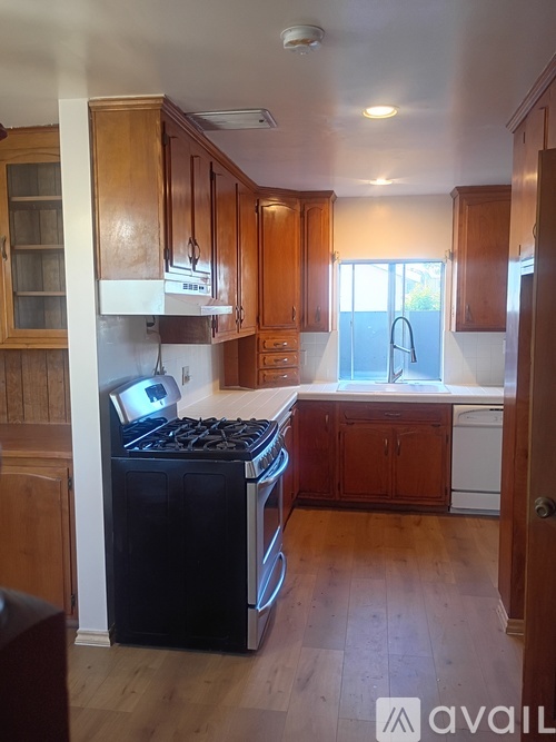 A kitchen with wooden cabinets and a black dishwasher.