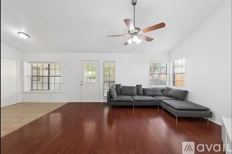 A living room with a grey sofa and a ceiling fan.