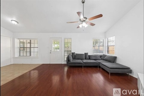 A living room with a grey sofa and a ceiling fan.