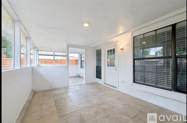 A spacious room with tiled flooring and large windows.