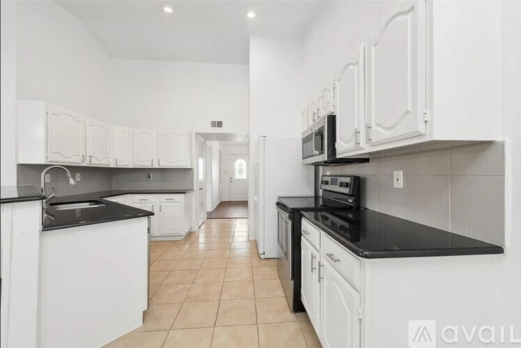 A kitchen with white cabinets and black countertops.