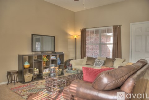 A living room with a brown leather couch and a television on a stand.