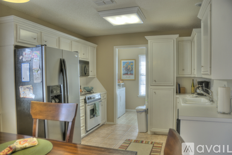 A kitchen with a refrigerator, sink, and cabinets.