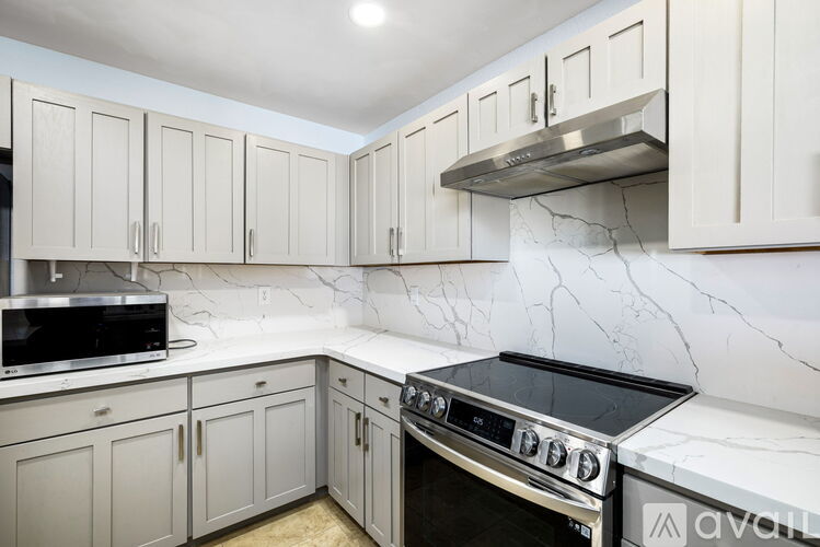 A kitchen with white cabinets and a marble backsplash.
