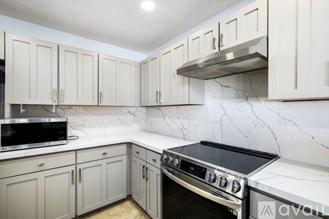 A kitchen with white cabinets and a marble backsplash.