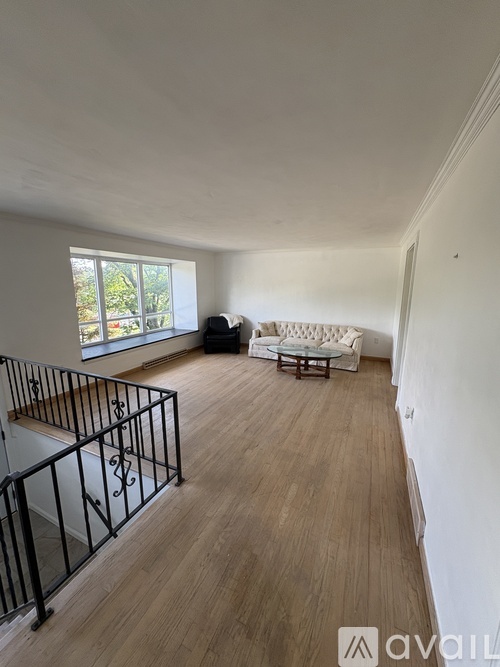 A living room with a white couch and a black metal railing.