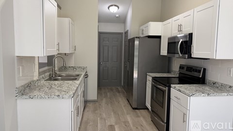 A kitchen with white cabinets and a granite countertop.