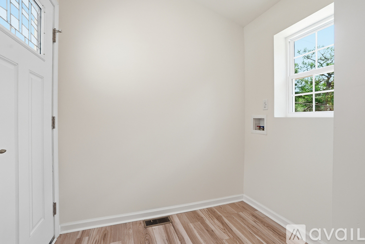 A room with a white door and a window with a view of trees outside.