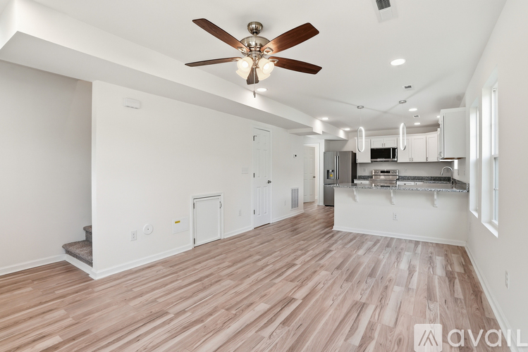 A spacious room with wooden flooring and a ceiling fan.