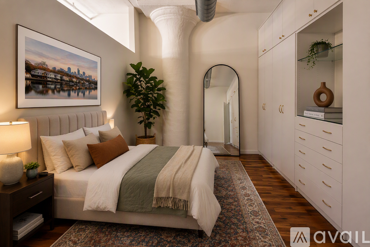 A bedroom with a bed, a lamp, a plant, and a painting on the wall.