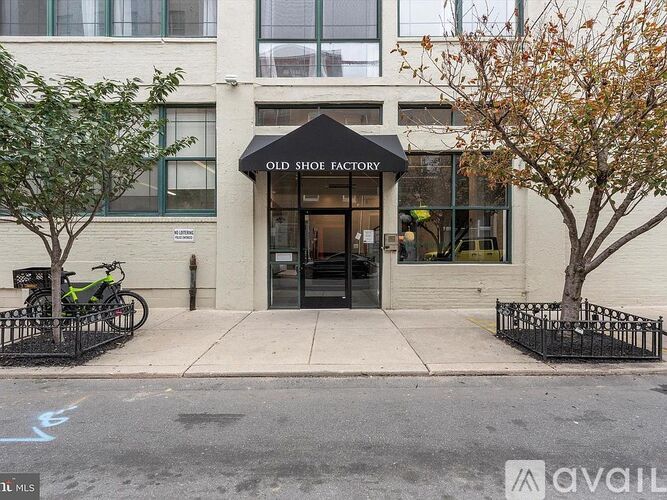 A black bicycle is parked on the sidewalk in front of a building with a sign that says Old Shoe Factory.