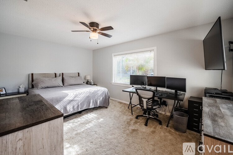 A bedroom with a bed, desk, and television.