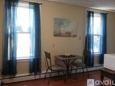 A dining room with a table, chairs and a painting on the wall.