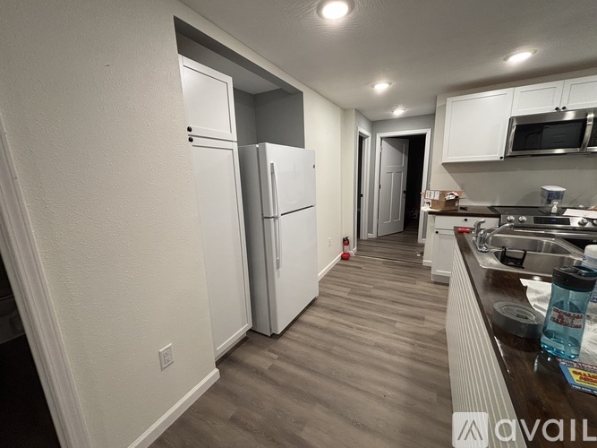 A kitchen with white appliances and a wooden floor.