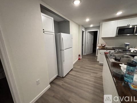 A kitchen with white appliances and a wooden floor.