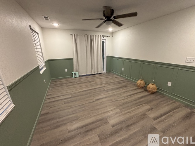 A room with a ceiling fan and wooden flooring.