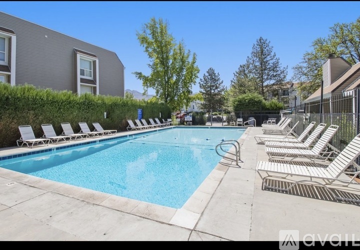 A pool surrounded by lounge chairs and trees.