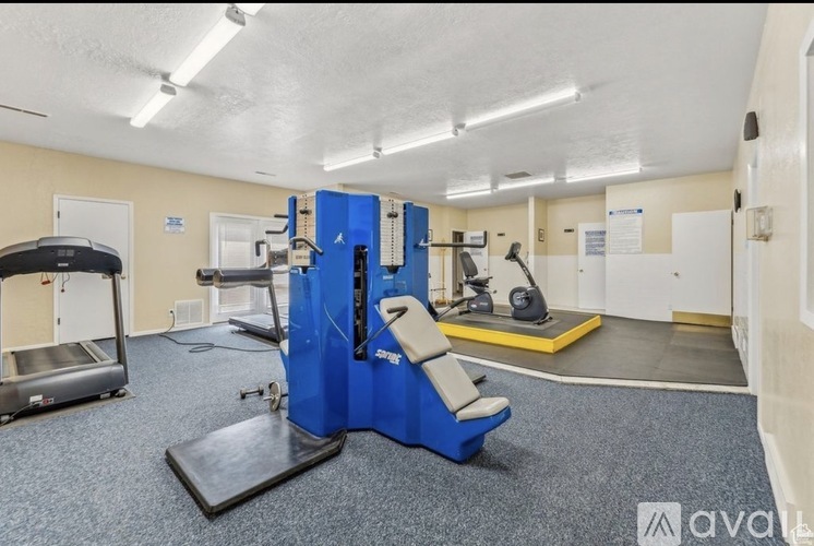 A gym with a variety of equipment including a treadmill, exercise bike, and weight bench.