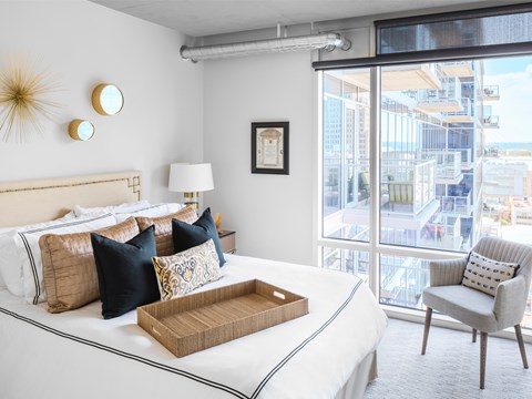 A bedroom with a large bed and a chair.