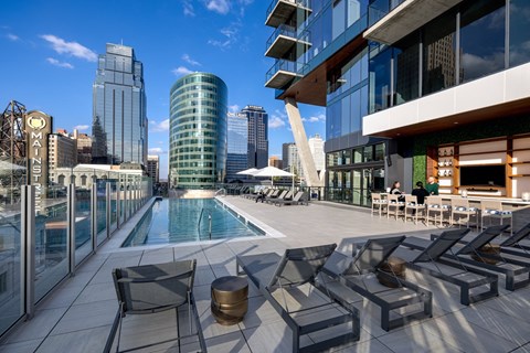 A rooftop pool area with loungers and a view of the city.