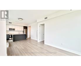 A spacious living room with a kitchen in the background.