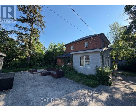 A house with a gravel driveway and a tree in front of it.