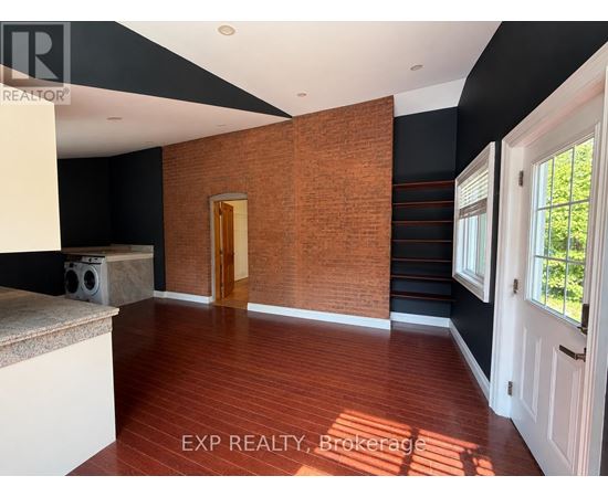 A room with a wooden floor and a brick wall.