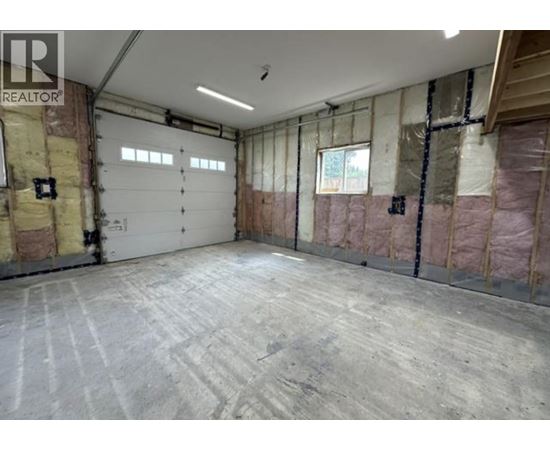 A spacious garage with a concrete floor and walls covered in insulation.