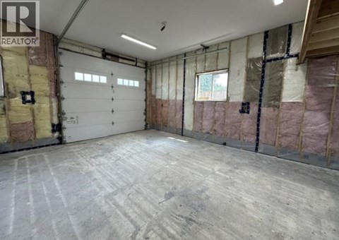 A spacious garage with a concrete floor and walls covered in insulation.