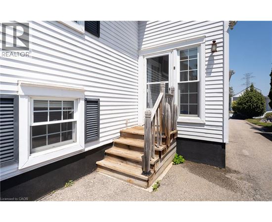 A white house with a wooden staircase leading to a door.