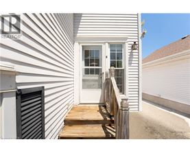 A white house with a wooden deck and a roller shutter door.