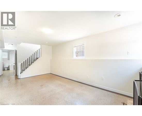 A spacious room with a staircase leading to the upper level.