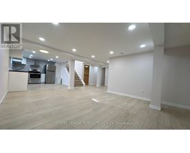 A spacious room with wooden flooring and white walls.