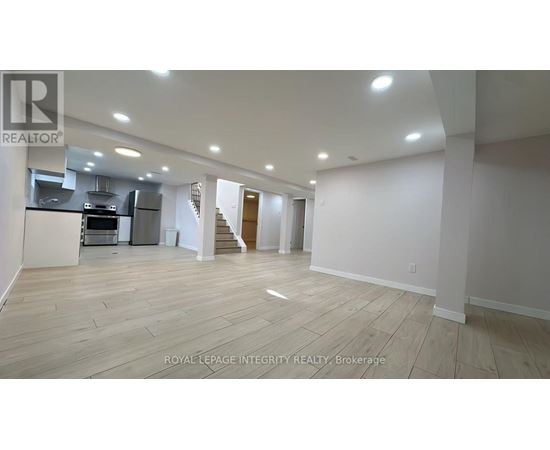 A spacious room with wooden flooring and white walls.
