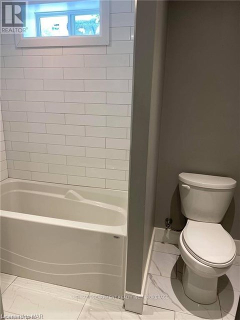 A white toilet sits next to a bathtub in a bathroom.