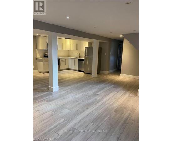 A spacious kitchen and living room with wooden flooring and modern appliances.