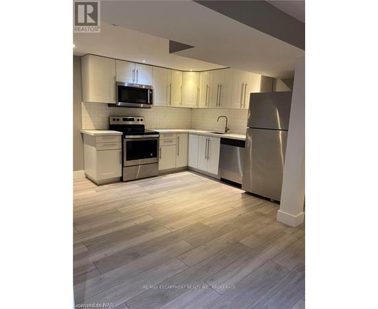 A kitchen with white cabinets and a refrigerator.