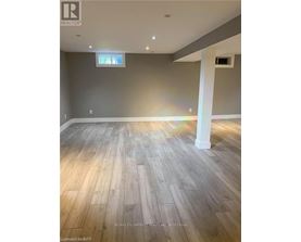 A room with wooden flooring and a grey wall.